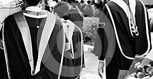 Black and white A group of male and female graduates wearing black robes outdoors on a rainy day in university concept graduating