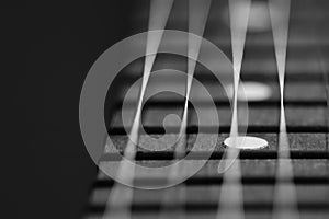 Black and white guitar fretoard bwith strings on black background