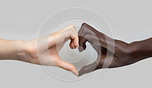 Black and white heart-shaped hands on a grey  background. The concept of inter-racial friendship and respect