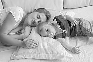 Black and white high point view photo of young mother sleeping next her baby boy lying in bed