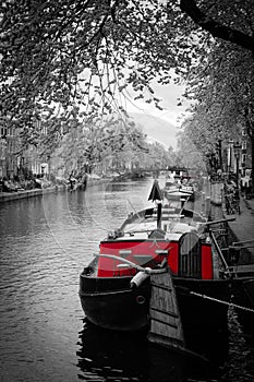 Black and white image of an amsterdam canal with red tug boat photo