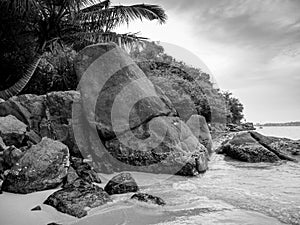 Black and white image of big rocks on the beach at tropical island lagoon