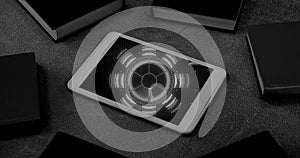 Black and white image of blue circular scanner processing data on screen of smartphone on desk