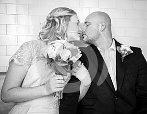 Black and White image of of bride and groom in vintage clothing sitting and kissing