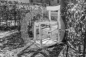 Black white image of a broken white chair in a garden Labyrinth, Germany