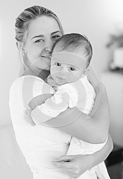 Black and white image of cheerful mother hugging her baby boy