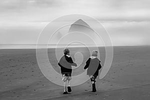 Young boys run on empty beach backs to camera