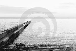 Black and white image of a concrete pier on the coast