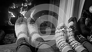 Black and white image of couple in woolen knitted socks relaxing by the fireside at home