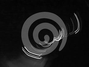 A black and white image of curved lines made by night lights.