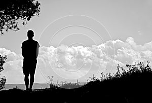 Silhouette in the field in front of a cloudy sky photo