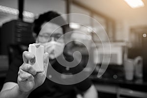 Black and white image of Hand is spraying alcohol with blurry businessman working in office