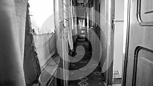 Black and white image of long narrow corridor in vintage train car