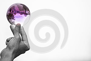 Black and white image of man holding delicate crystal ball between finger and thumb