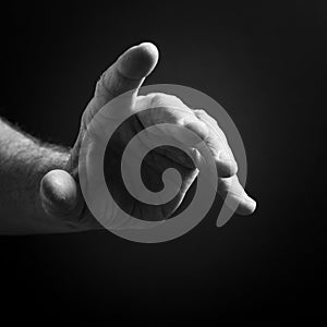 Black & white image of man`s hand pointing, isolated against a black background with dramatic sidelight