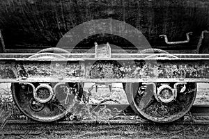 A black and white image of old vintage rusty railway coal cart wheels