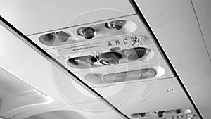 Black and white image of passenger control panel on the ceiling of jet airplane