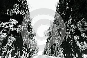 A black and white image of a road going through a rocky mountain photo