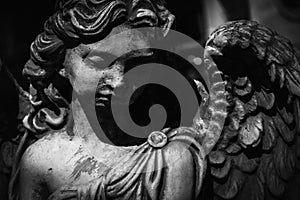 Black and white image of sad angel of death. Fragment of an ancient statue