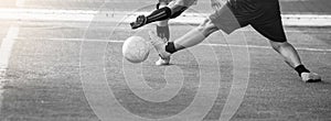 Black and white image. Selective focus to soccer player speed run to control and shoot ball to goal