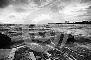 Soft wave flow hitting the sandy beach over dark cloud background