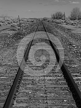 Black and white image of train tracks traveling through open land in Nevada