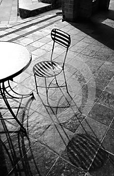 two chairs at an outdoor table facing each other in black and white