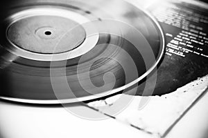 A black-and-white image of a vinyl record lying paper on the album cover