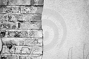 Black and white image of a wall, half brick and half stucco photo