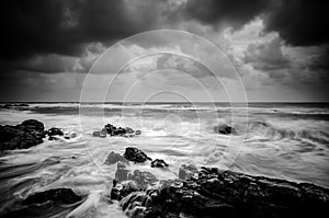 Black and white image wave hitting the coastline with dramatic cloud