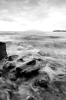 black and white image wave hitting the coastline