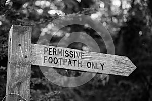 Black and white image of a wooden permissive footpath sign photo