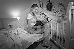 Black and white image of young mother reading book to her baby b
