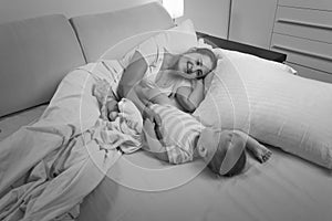 Black and white image of young mother sleeping with her baby boy