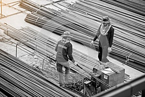 Black and white imahe of construction worker and many deformed steel bar working with hydraulic rebar cutting machine at the