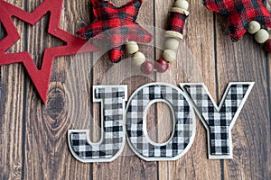 Black and white joy plaid phrase on a wood background with red stars, useful for Christmas projects