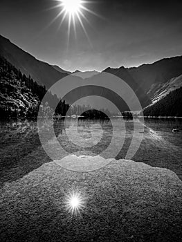 Black and White landscape photo of sun casting its rays over Avalance Lake photo