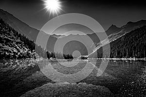 Black and White landscape photo of sun casting its rays over Avalance Lake photo