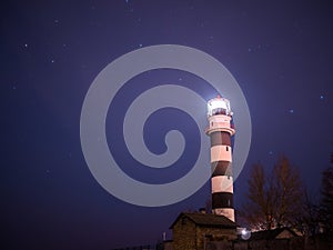 Black and white lighthouse at night in Baltic sea beach