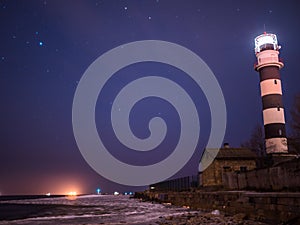 Black and white lighthouse at night in Baltic sea beach