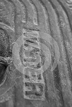 A black and white macro detail of an old steel water meter cover dug out of the ground