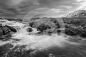 Black and white Majestic Winter landscape image of River Etive in foreground with iconic snowcapped Stob Dearg Buachaille Etive