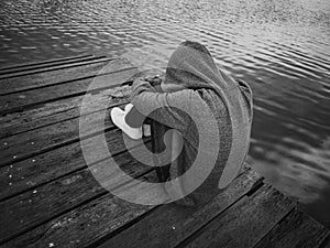 Black and White The man sitting on a pier beside the lake. Alone, lonely, sad Concept