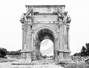 Black and white medium shot of iconic Arch of Septimius Severus at ancient Roman ruins of Leptis Magna in Libya