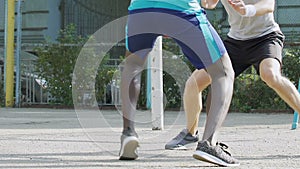 Black and white men playing basketball outside summer, dribbling, competition