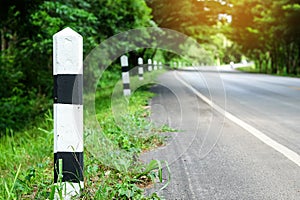 Black and white milestones with green grass roadside, Trees road