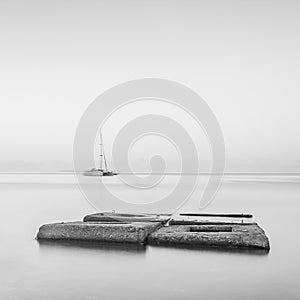 Black & White minimalist seascape with ship and rocks.