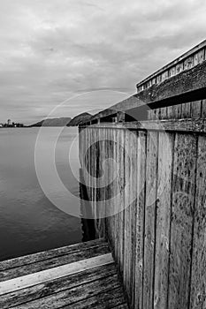 Black And White Monochrome Image Wooden Dock Board Walk Structure At Waters Edge