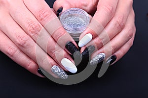 Black, white Nail art manicure. Holiday style bright Manicure with sparkles. Bottle of Nail Polish. Beauty hands