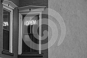 Black and white neon OPEN sign in building window